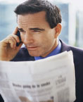 Male executive speaking on mobile with newspaper in his hand